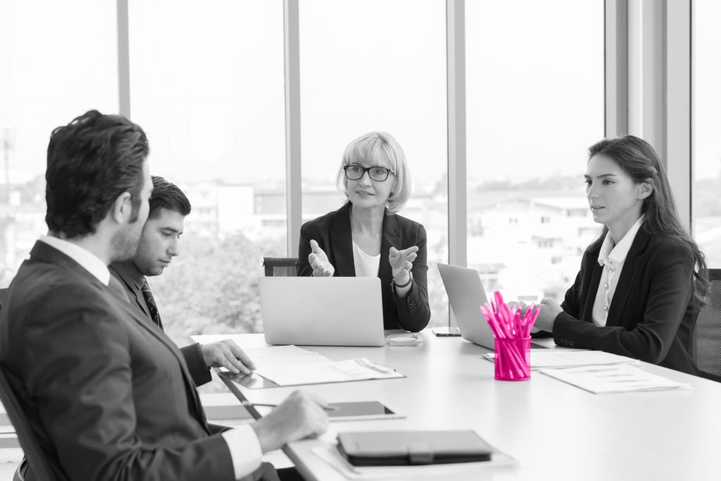 Image shows two women and two men sat at an office table negotiating divorce.